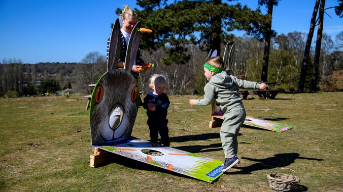 Children throwing fabric carrots into a wooden cut out of a hare as they take part in the Easter trail at Sutton Hoo
